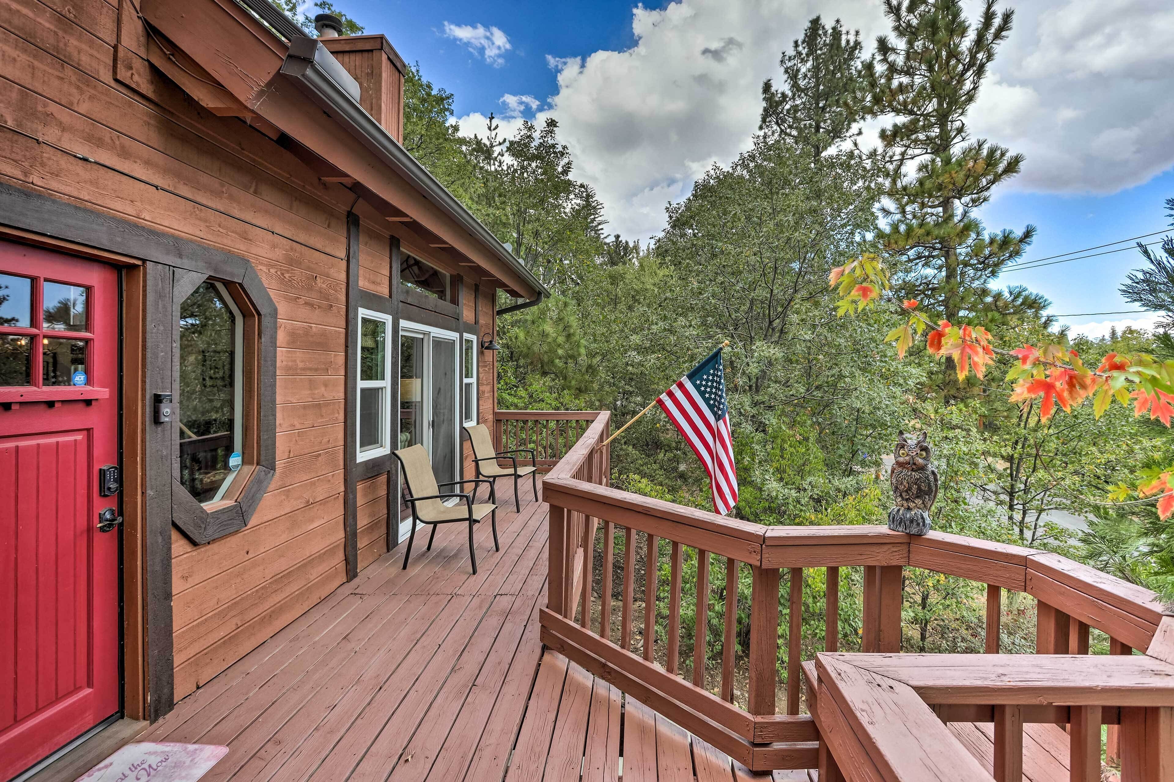Eine Holzterrasse mit einer roten Tür, zwei Fenstern und einer kleinen amerikanischen Flagge.