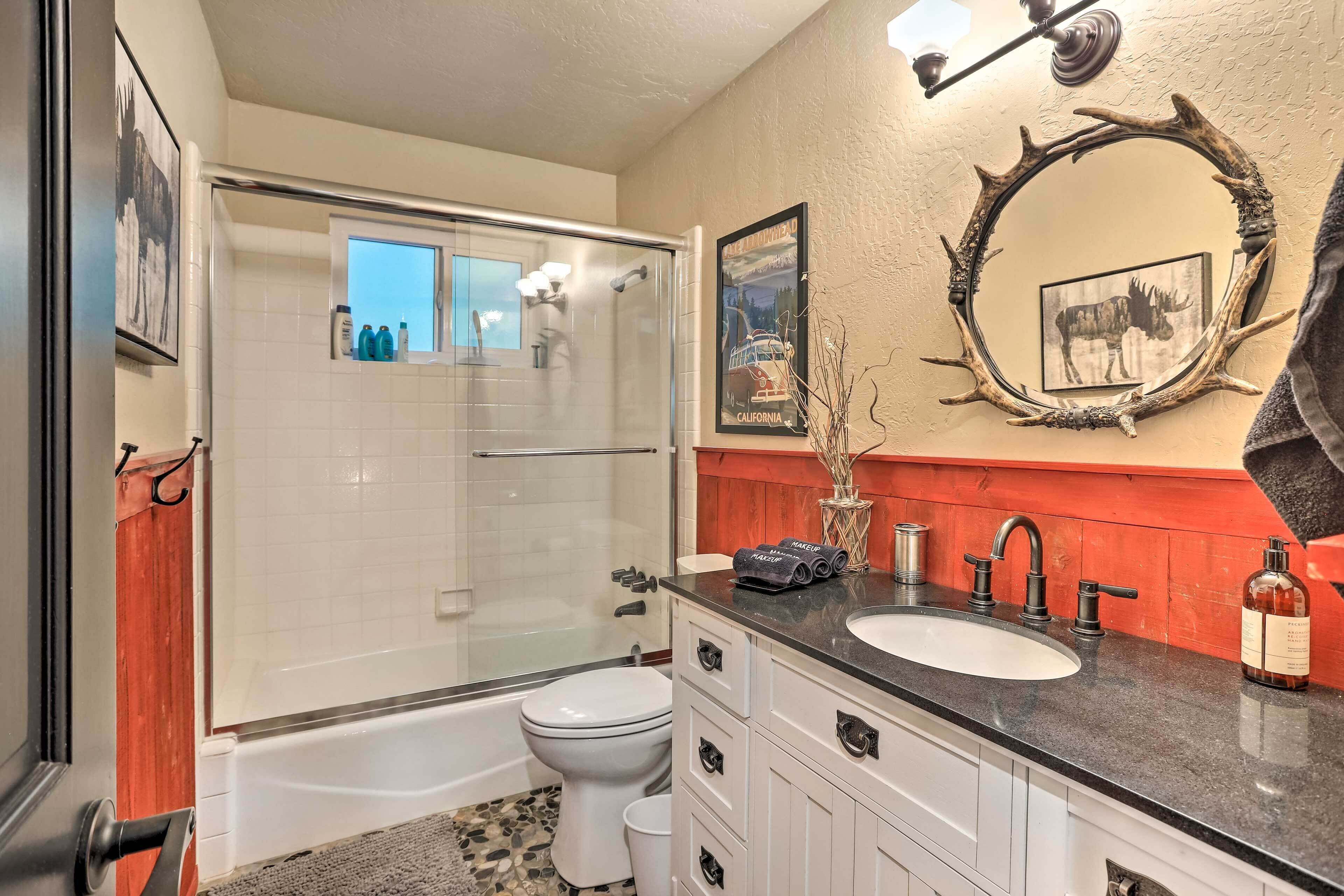 A bathroom with a glass-enclosed shower, a white toilet, a bathtub, and a vanity with a sink and mirror.