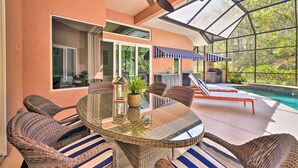 A glass-enclosed patio with wicker furniture, a pool, and a view of the outdoors. - Pet-friendly Resort Home: Private Pool + Spa! (Bradenton)