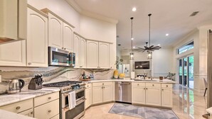 A spacious kitchen with white cabinetry, a large island, stainless steel appliances, and a marble backsplash. - Pet-friendly Resort Home: Private Pool + Spa! (Bradenton)