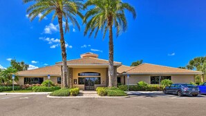 A two-story building with a tiled roof, a central entrance, and a parking lot with two cars. - Pet-friendly Resort Home: Private Pool + Spa! (Bradenton)