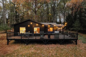 A cabin with a deck, surrounded by trees.