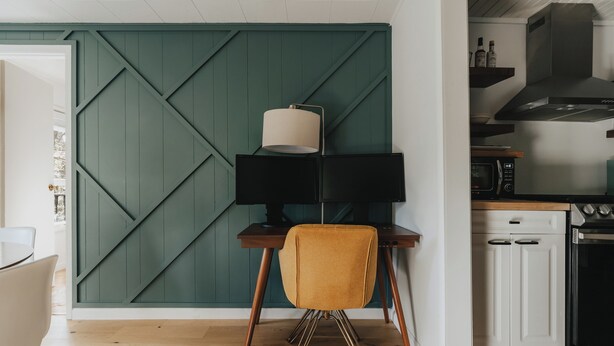 Une cuisine moderne avec un mur d’accent vert, un coin repas avec une table et des chaises, et un four à micro-ondes.