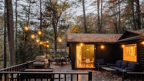 Un chalet confortable doté d’une terrasse, de meubles d’extérieur et de guirlandes lumineuses.
