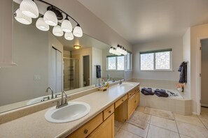 Features a large vanity with two sinks, a spacious bathtub, and a large mirror.