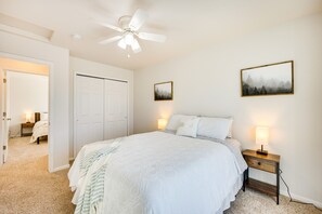 Relax in this serene bedroom with a large bed, bedside tables, and ceiling fan.