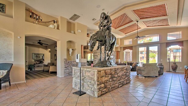 Eine geräumige Lobby mit Kamin aus Stein, einer Statue eines Reiters auf einem Pferd und einer hohen Decke mit Holzbalken.