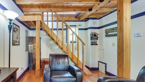 Una habitación con una escalera de madera, un sillón de cuero negro y una mesa de madera.