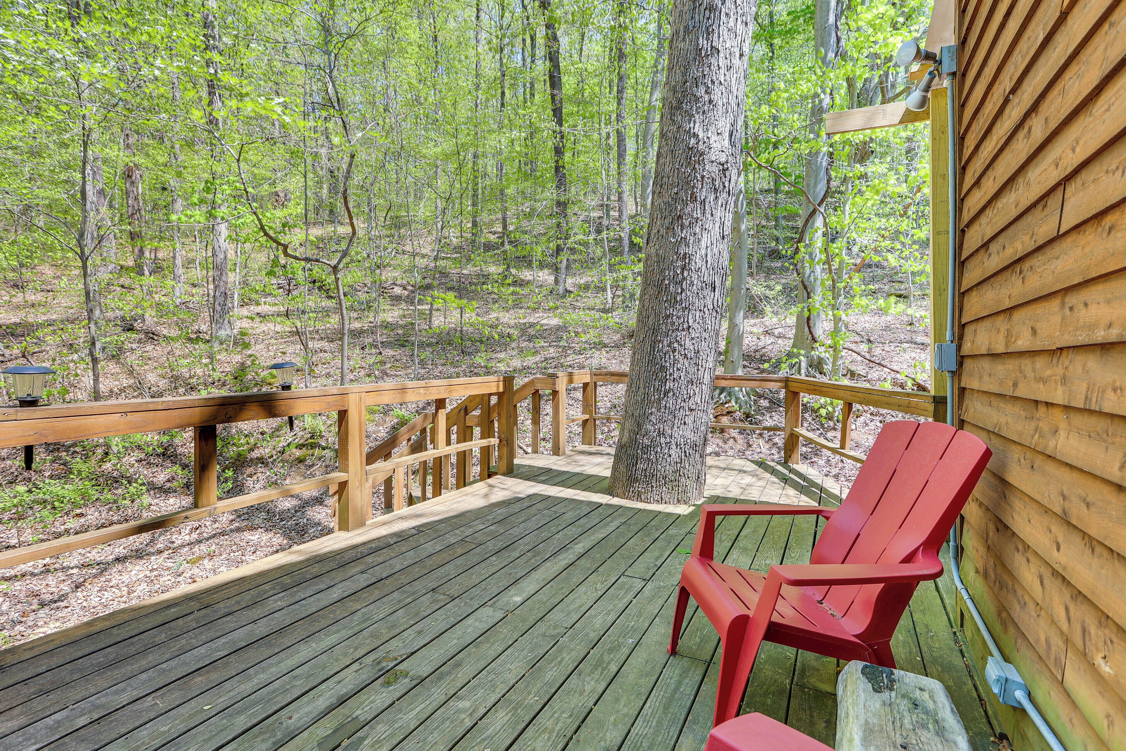 A wooden deck with a red chair, surrounded by trees.