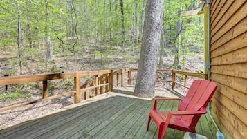 A wooden deck with a red chair, surrounded by trees.