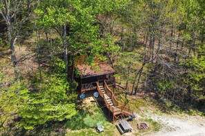 An elevated wooden cabin with a deck, surrounded by dense forest. - Dreamy Indiana Cabin Rental w/ Shared Amenities! (Taswell)