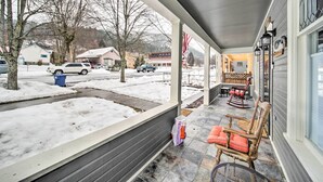 A covered porch with outdoor seating, a snow-covered driveway, and a view of the neighborhood. - Charming Kellogg Home Near Outdoor Activities (Kellogg)