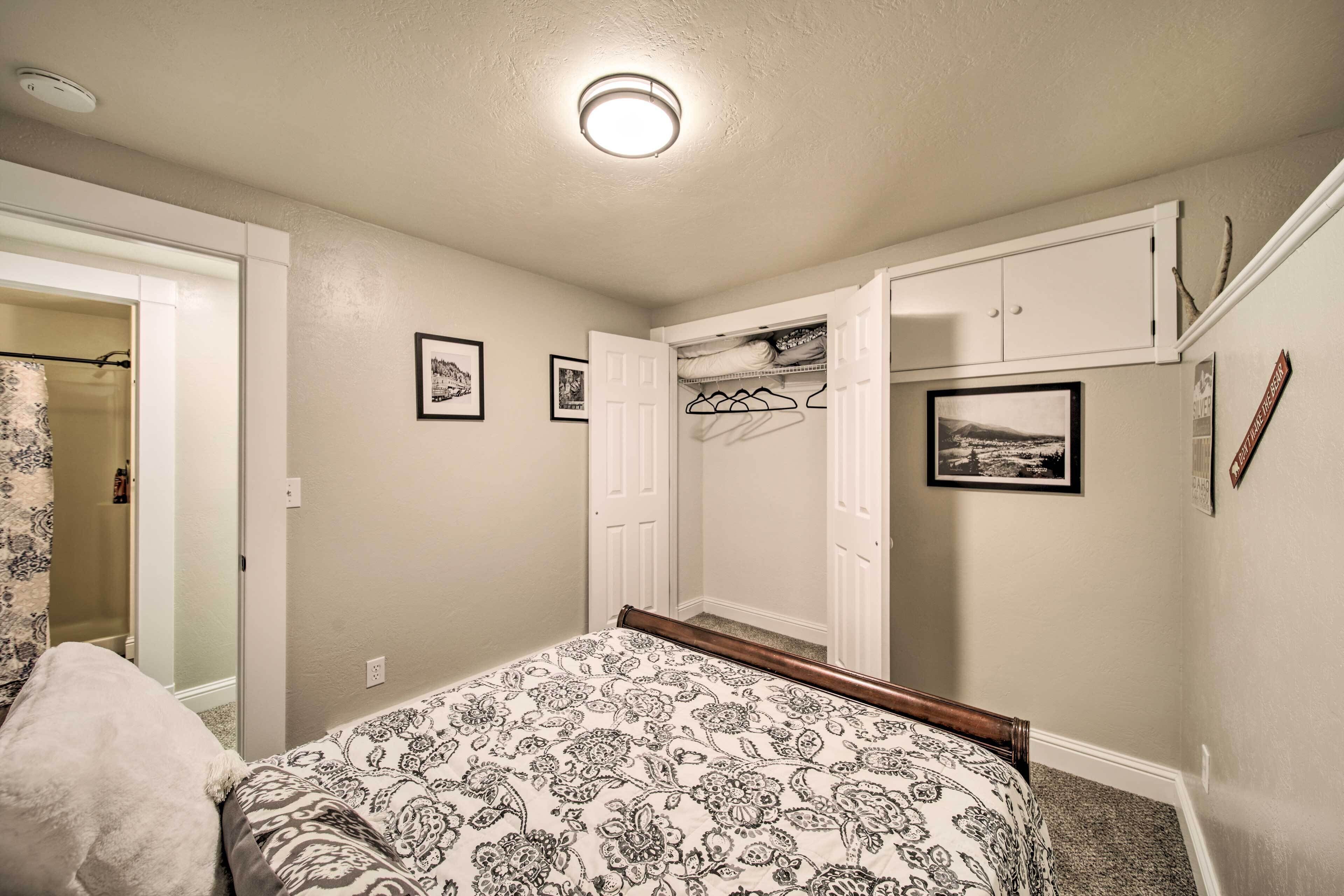 Quarto com uma cama, um guarda-roupa e um pequeno espaço de armazenamento com prateleiras.