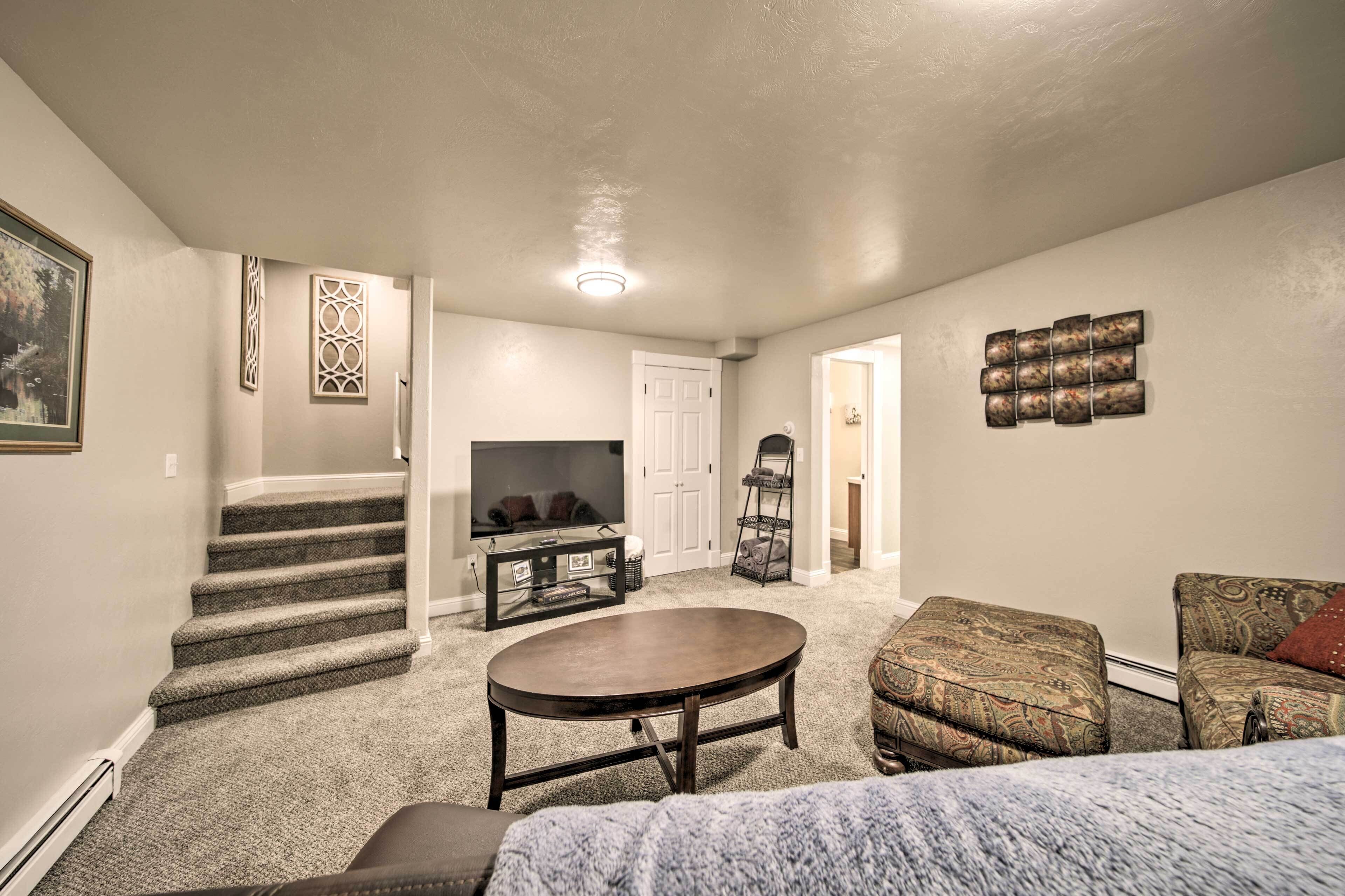 A living room with a fireplace, a TV, a staircase, and a door leading to another room.