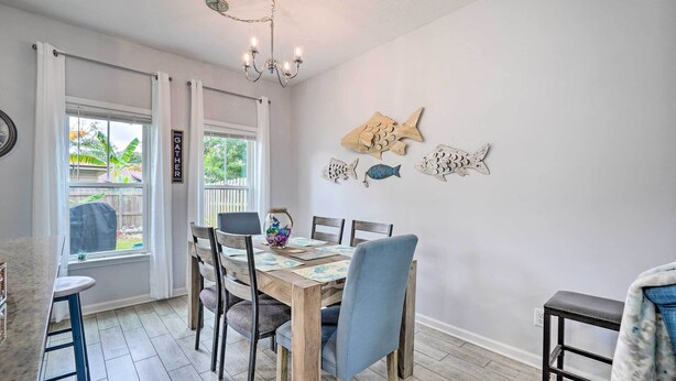 Un espace repas avec une table et des chaises en bois, un lustre et des décorations murales représentant des poissons.