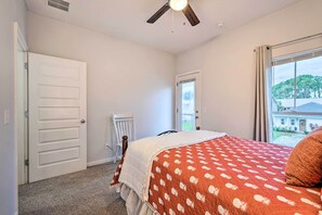 Un dormitorio con cama, ventilador de techo, ventana con vistas y puerta.