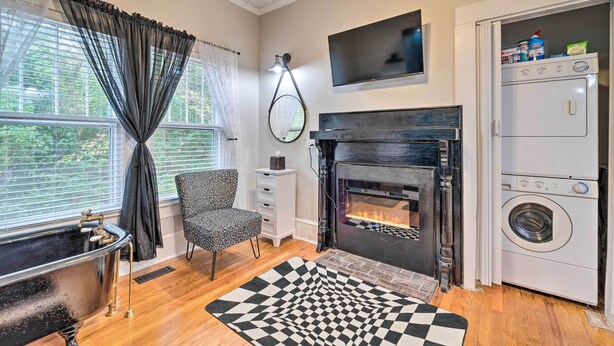 A modern living room with a fireplace, a black bathtub, a flat-screen TV, and a washing machine. - Burgaw House w/ Large Covered Porch & Swing! (Burgaw)