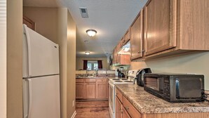 A kitchen with wooden cabinets, a refrigerator, a microwave, and a stove.