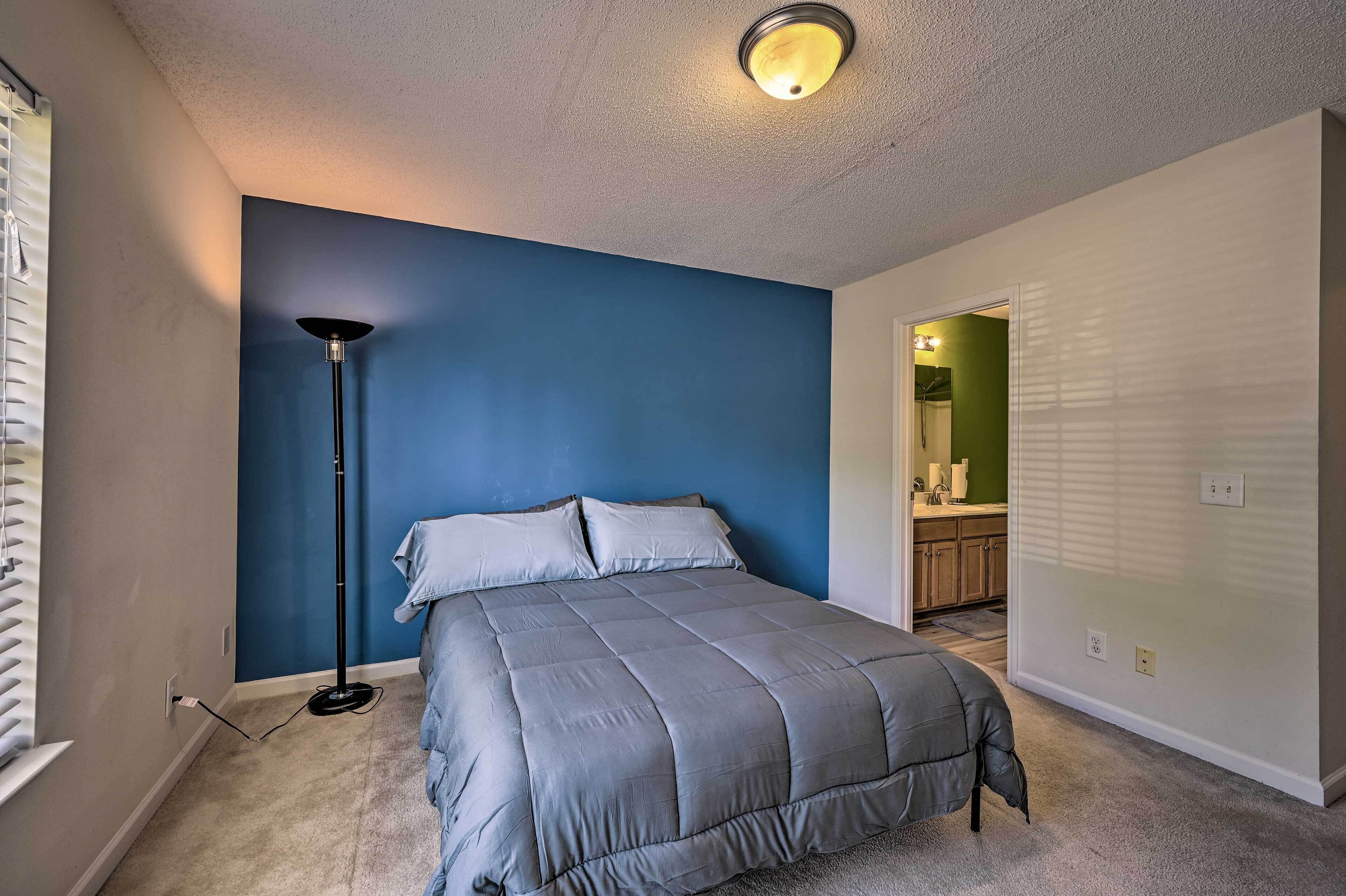 A bedroom with a bed, a standing floor lamp, and a ceiling light fixture.