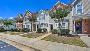 A row of townhouses with a front yard, a driveway, and a street.