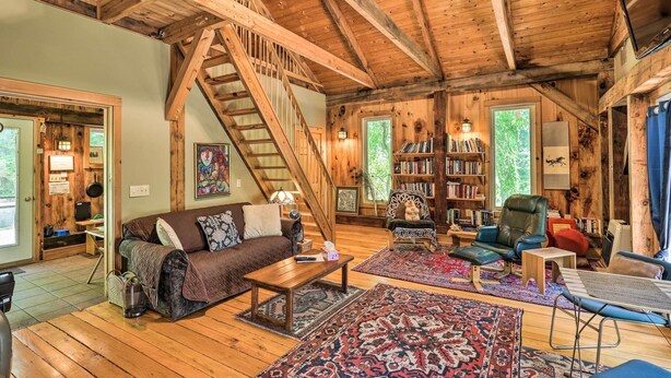 Un salon spacieux avec un escalier en bois, un canapé, une table basse, une bibliothèque et une grande fenêtre.