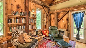 Une pièce chaleureuse aux murs en bois, avec une bibliothèque, un fauteuil en cuir, un fauteuil à bascule et un tapis rouge à motifs.