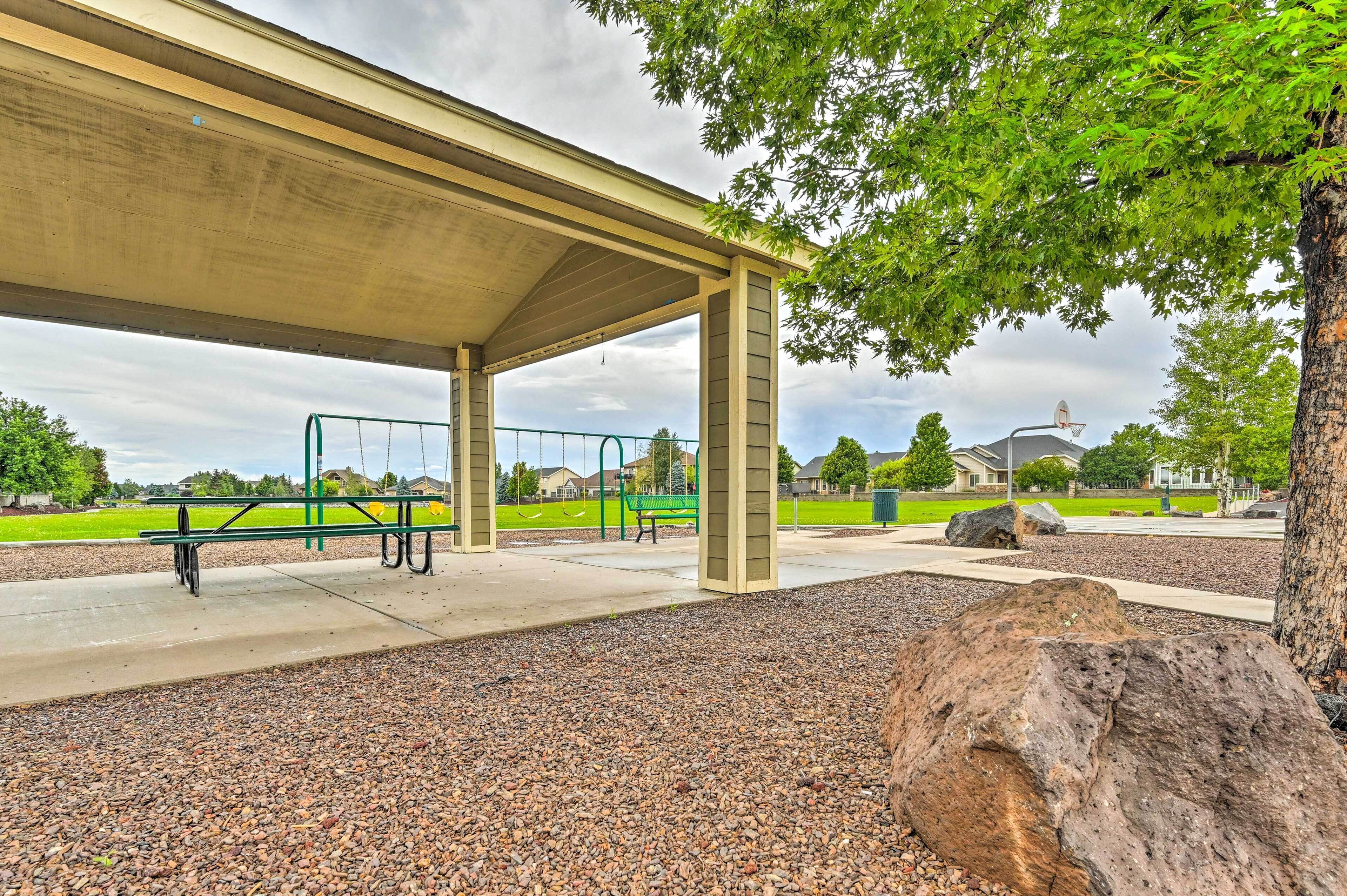 A covered picnic area with benches and a playground in the background.