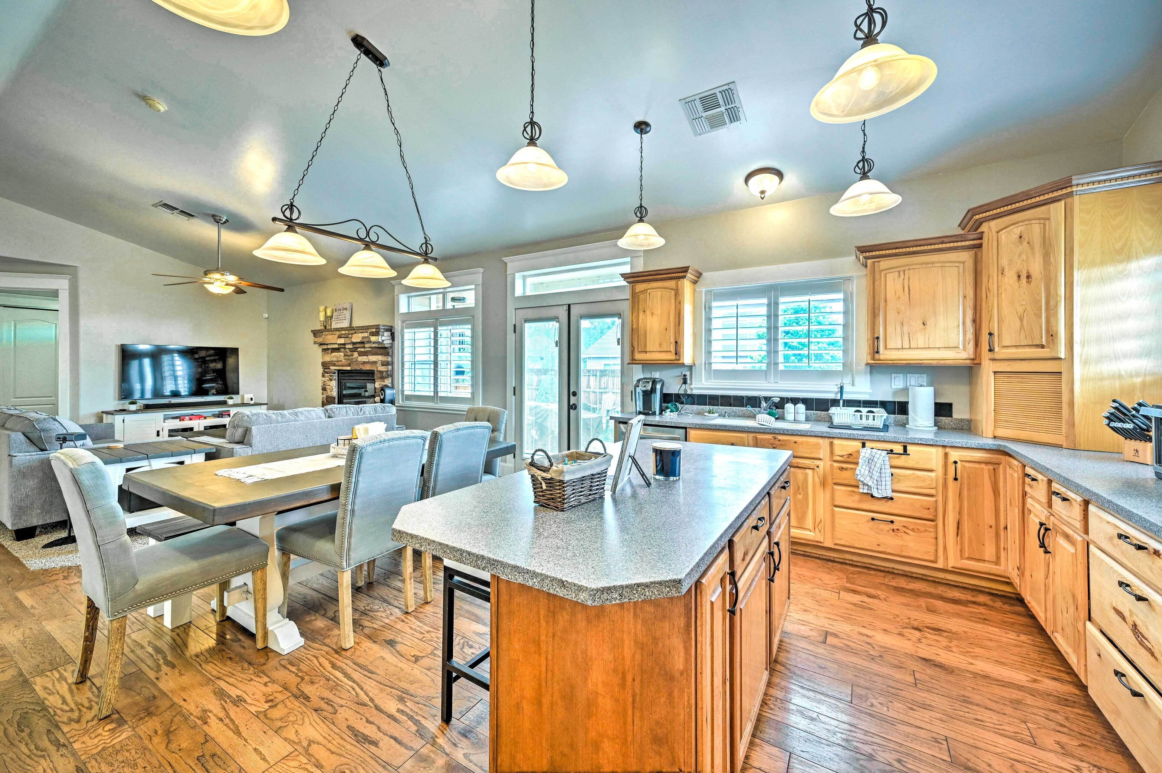 A spacious kitchen with wooden cabinets, a large island, and pendant lighting.