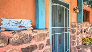 A stone wall with a sign reading "Hummingbird" and a blue door. - Artsy Santa Cruz Apartment w/ Shared Fire Pit! (Santa Cruz)