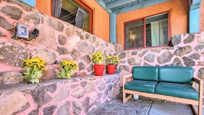 A stone wall with potted sunflowers and a green bench. - Artsy Santa Cruz Apartment w/ Shared Fire Pit! (Santa Cruz)