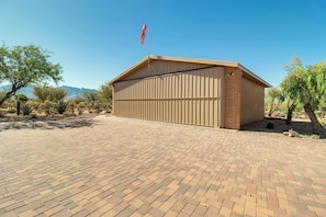 A single-story building with a flat roof, a flag on top, and a paved driveway leading to the entrance.