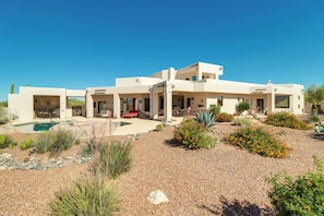 A modern house with a pool, outdoor seating, and desert landscaping.
