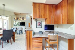A modern kitchen with wooden cabinets, a dining area with chairs, and a TV. - Oro Valley Airpark Estate w/ Pool & Mtn Views (Oro Valley)