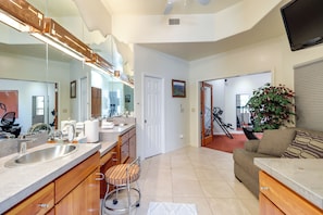 A modern kitchen with a large island, stainless steel appliances, and a view into the living area.