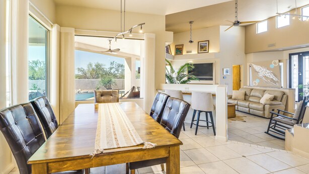 A spacious living area with a dining table, chairs, a sofa, and a TV. - Mtn-view Oasis w/ Pool, Spa & Gym in Oro Valley! (Oro Valley)