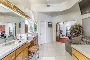 A modern kitchen with a large island, a dining area with a sofa, and a living room with a TV.