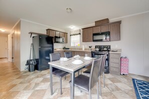A modern kitchen with a dining table set for four, a refrigerator, microwave, and oven. - Cozy Cabin: Community Pool & Lakefront Beach! (Cassopolis)