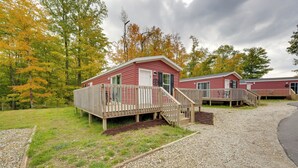 A red cabin with a wooden deck and a gravel path leading to it. - Cozy Cabin: Community Pool & Lakefront Beach! (Cassopolis)