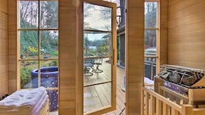 A sauna room with a wooden bench, a towel, and a sauna heater. - Tranquil Abode w/ Garden, Sauna & Cold Plunge (Asheville)