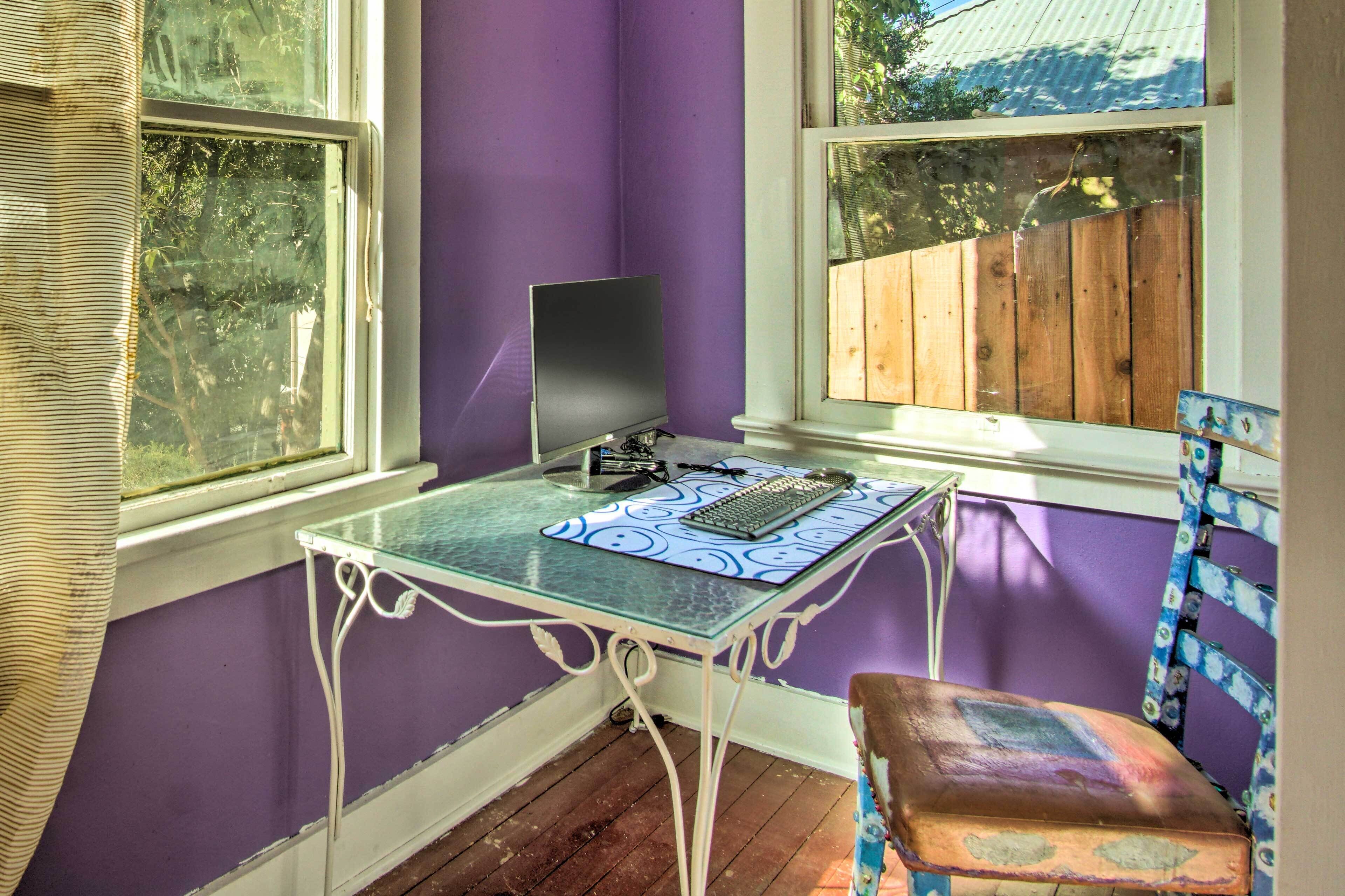 A room with purple walls, a glass table with a keyboard, and a chair.