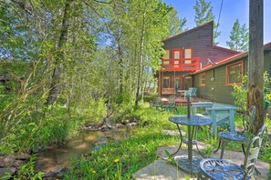 A cabin with a red roof and green walls, surrounded by a natural setting with a stream and greenery. - Cozy Creekside Cabin in La Veta: Hike & Fish! (La Veta)