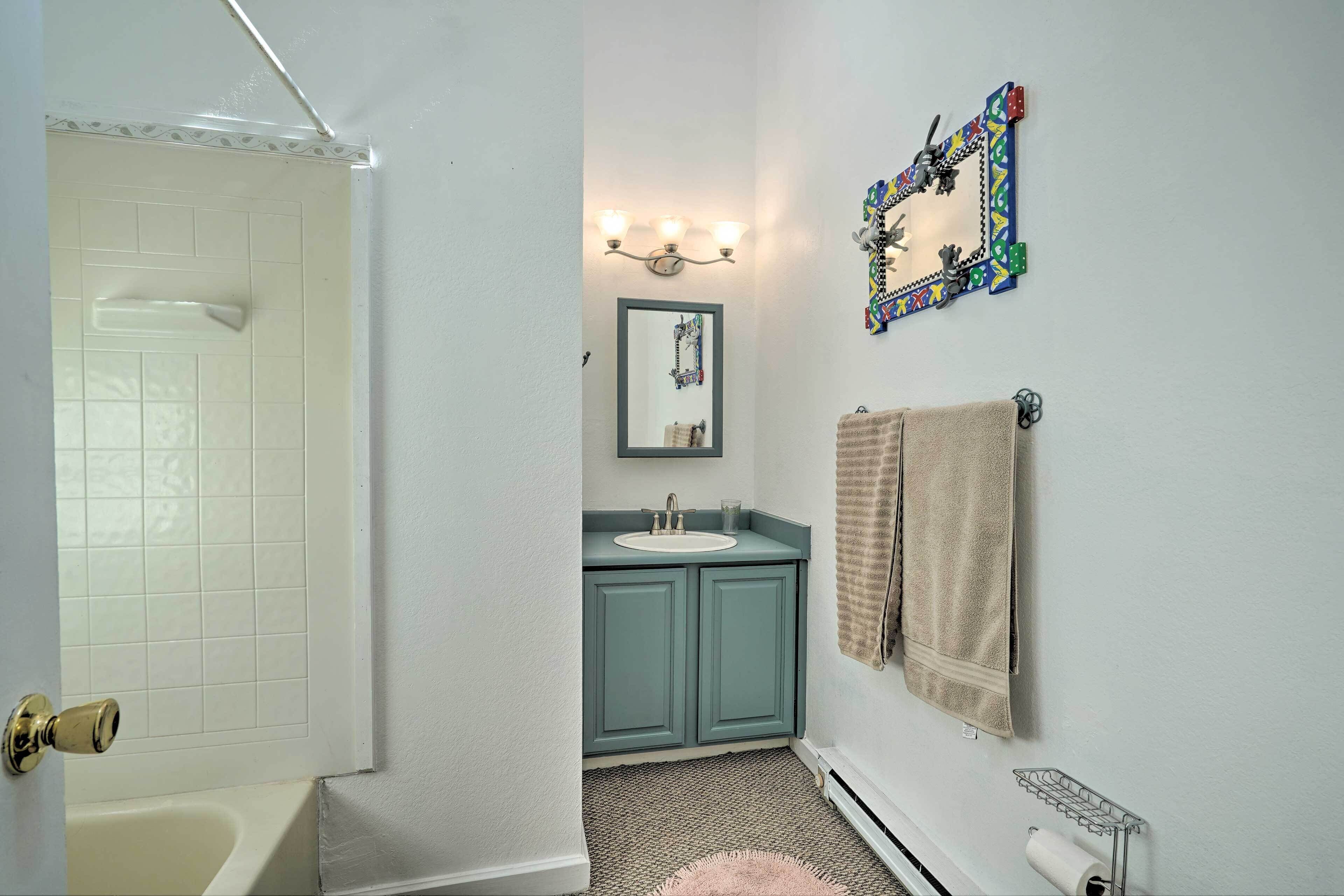 A bathroom with a white bathtub, a sink with a mirror above it, and a towel rack.
