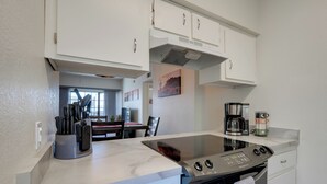 A modern kitchen with white cabinets, a built-in stove, and a coffee maker.