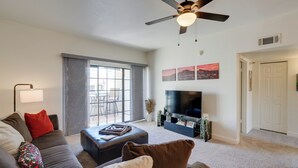 A modern living room with a sofa, ottoman, and a flat-screen TV.