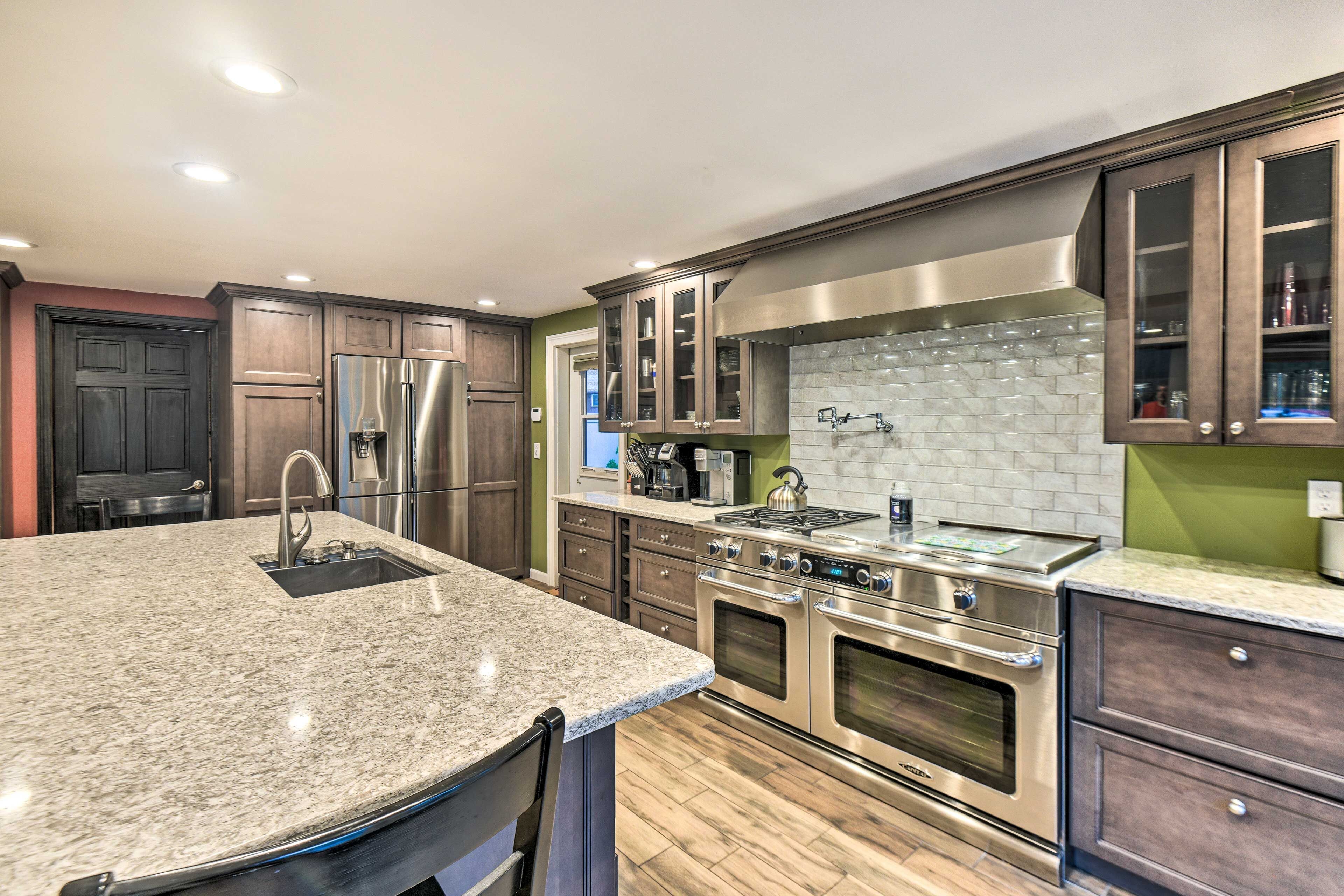 Una cocina moderna con encimeras de granito, electrodomésticos de acero inoxidable y armarios de madera oscura.