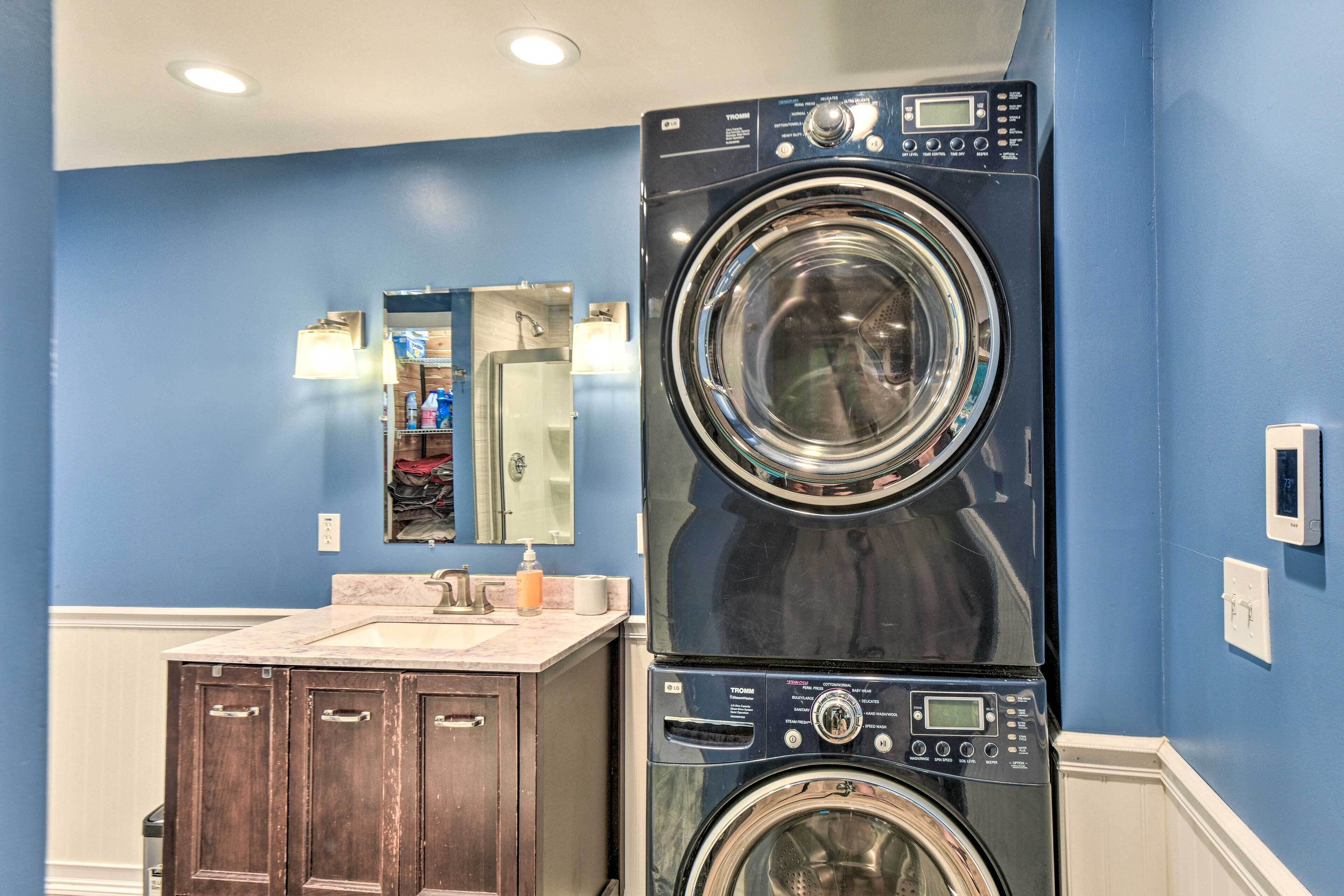 A laundry area with two stacked front-loading washing machines, a sink, and a mirror above the sink.