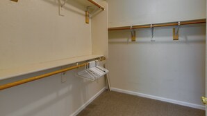 A room with a wooden beam ceiling, white walls, and a beige carpet. There are two wooden beams with white hangers and a wooden ladder leaning against the wall. - Gilbert Home w/ Pool < 5 Mi to Downtown! (Gilbert)