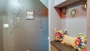 A staircase with beige carpet and wooden steps, a wall with decorative metal branches and a framed picture, and a sofa with floral cushions.