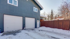 A two-car garage attached to a house with a wooden fence and snow on the ground.