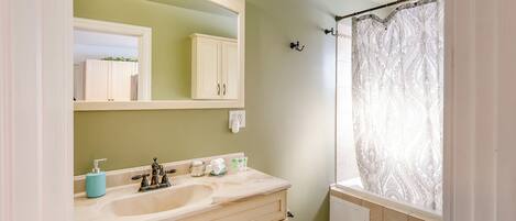 A bathroom with a beige vanity, a large mirror, a sink, and a toilet.